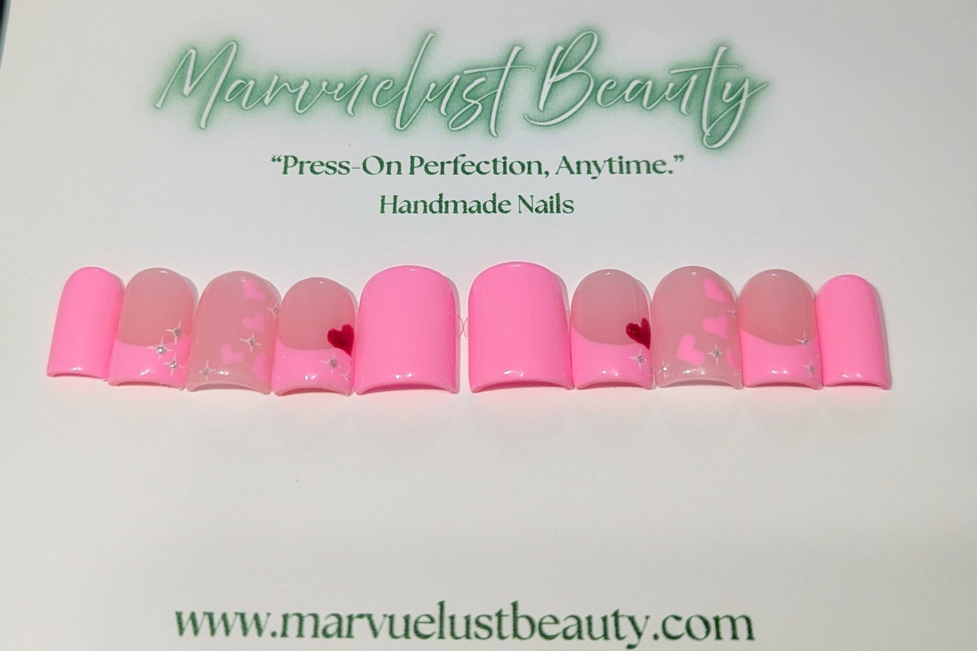 Soft pink press-on nails with decorative elements on a white background, featuring 'Marvuelust Beauty' branding.
