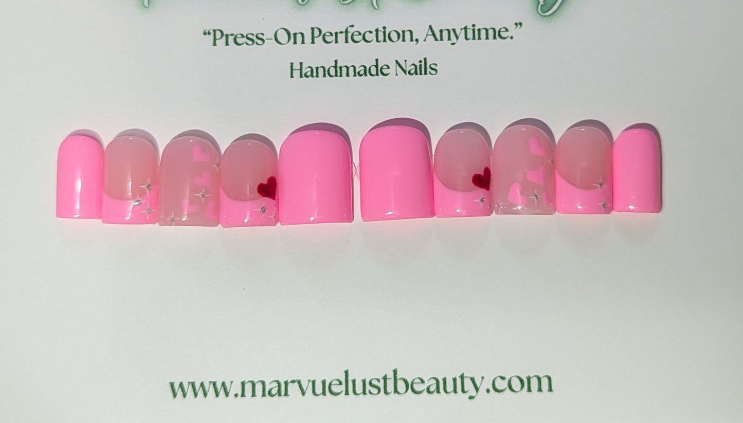 Set of pink press-on nails with heart designs on a white background, featuring the brand 'Marvuelustbeauty'.