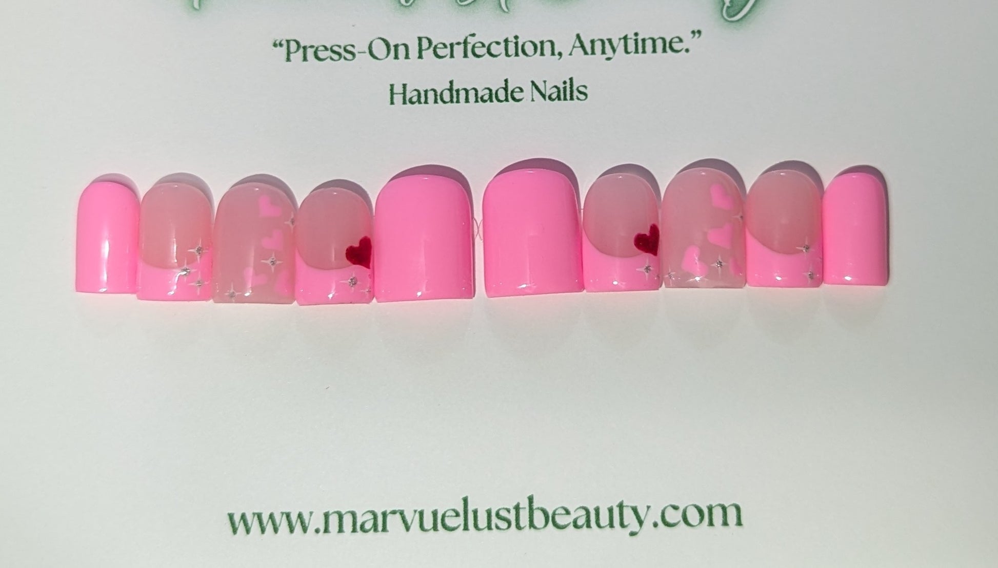 Set of pink press-on nails with heart designs on a white background, featuring the brand 'Marvuelustbeauty'.