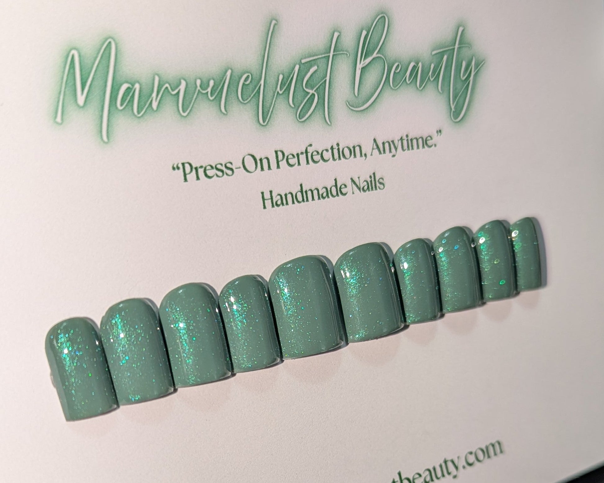 Set of green glittery press-on nails on a white background with 'Marvuelust Beauty' branding.